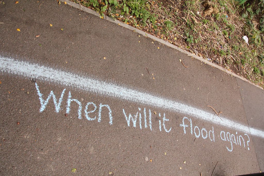 A line on the pavement with the words 'when will it flood again?' underneath.