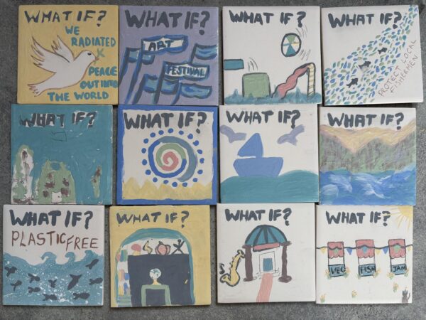 A set of brightly decorated ceramic tiles each headed with What If? and followed by pictures depicting a playground, fish, boats, and abstract shapes, and words saying 'protect local fishermen', 'plastic free' and 'art festival'.