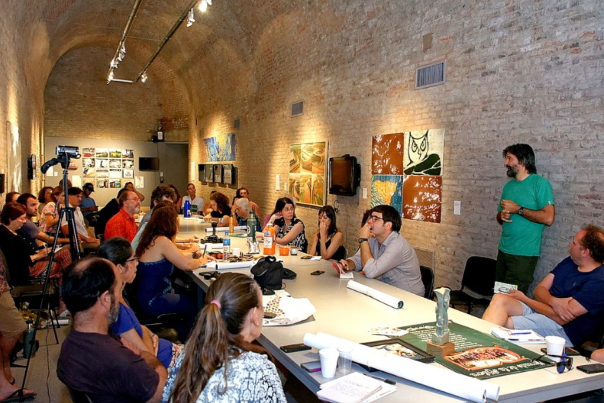 A group of people sitting at a long table in a brick room