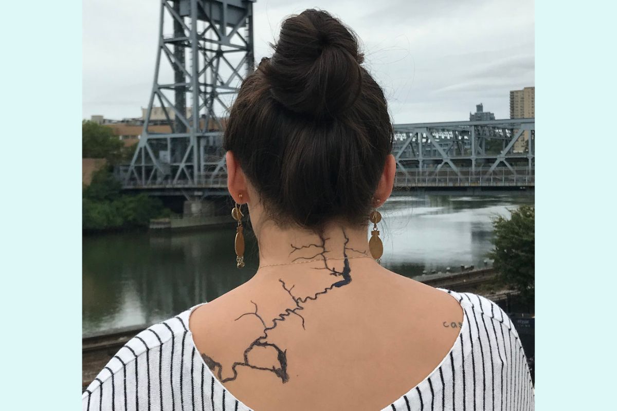 Back of a tattooed person looking at a river