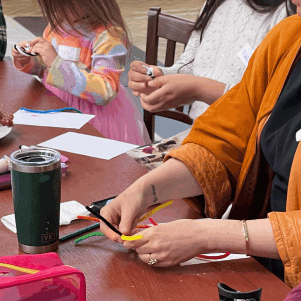Close-up of three people sculpting with multicoloured pipe cleaners.