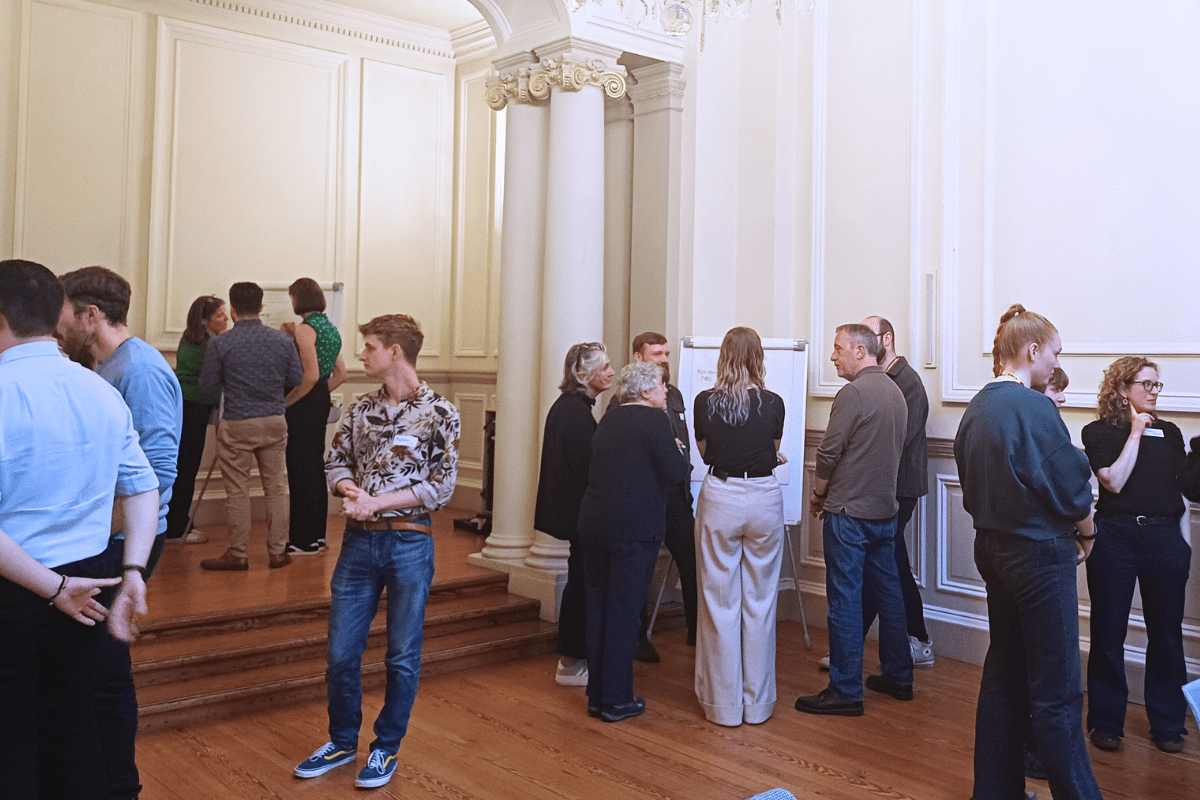 Group discussions around flip charts in a room with white walls and a wooden floor.