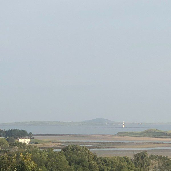 Looking out to a large light house and a bay with land on the other side