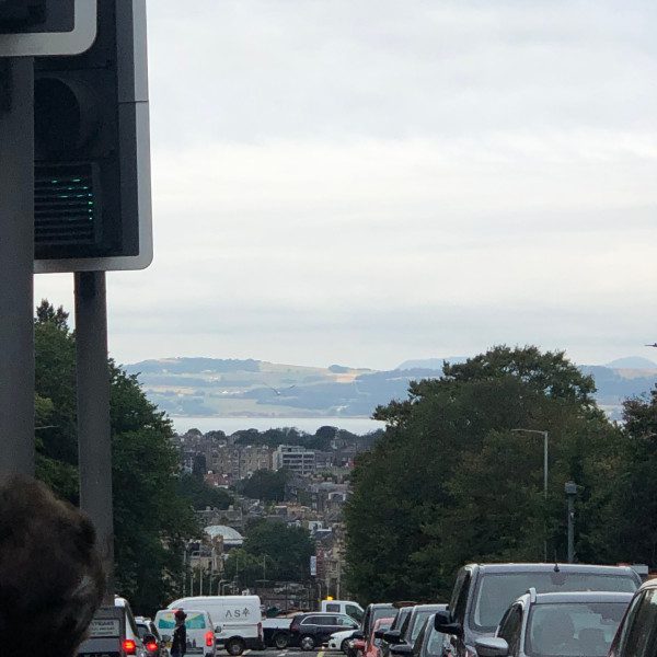 Looking from a busy street towards the sea and the land on the other side.