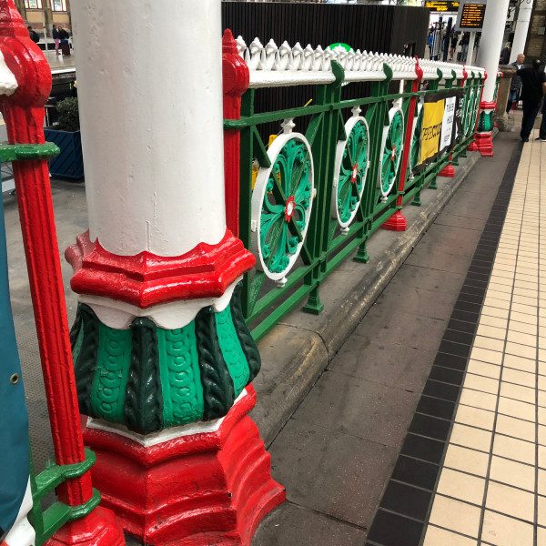 Colourful, painted pillar and railing in a railway station.