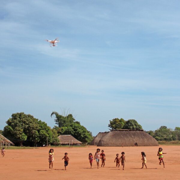 Children running under a drone in an Indigenous village