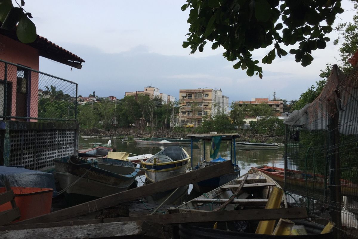 A view of boats at the side of the river, in the background, across the river, there are tall residential buildings.