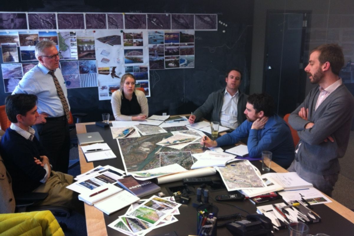 People sitting and standing around a table with many maps, printouts and documents at the East Bowmont Park design session