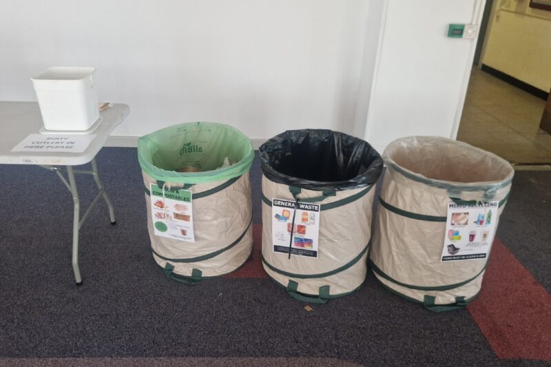 Three waste bins with signs and a container for dirty cutlery.