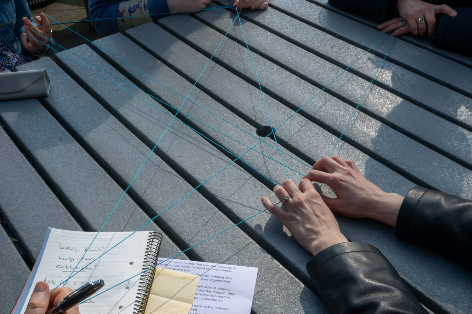 Five people holding a web of blue string.