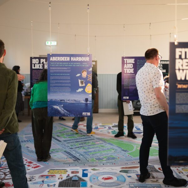 People looking at hanging posters and floor maps about place-based projects and initiatives.