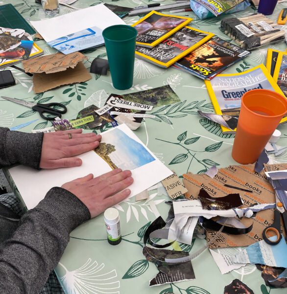 A table covered in old magazines. People are tearing out pieces to make into collages.